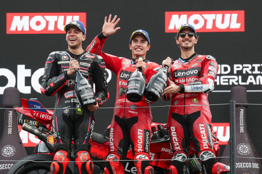 Marc Marquez celebrates with Marco Bezecchi and Francesco Bagnaia on the Assen podium after winning the 2025 MotoGP Dutch Grand Prix.