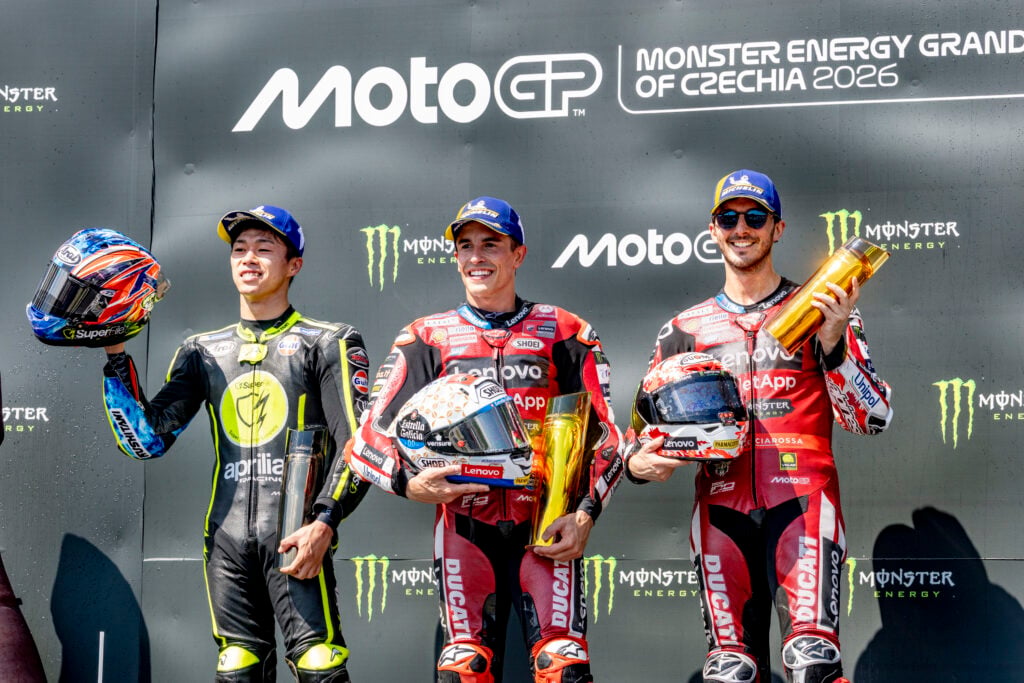 Ducati rider Marc Marquez celebrates winning the 2026 MotoGP Czech Grand Prix on the Brno podium with Ai Ogura and Francesco Bagnaia